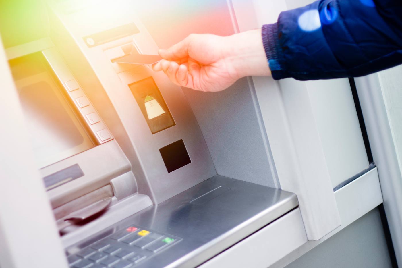 Person inserting card into ATM machine with illuminated card slot