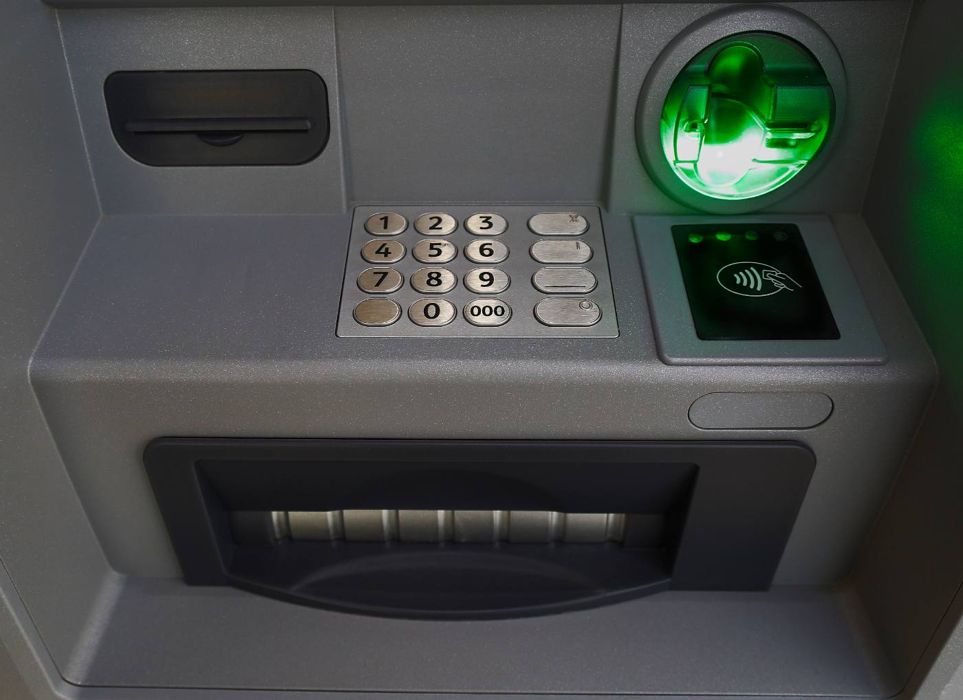 Close-up of ATM keypad, card reader, and illuminated green display screen