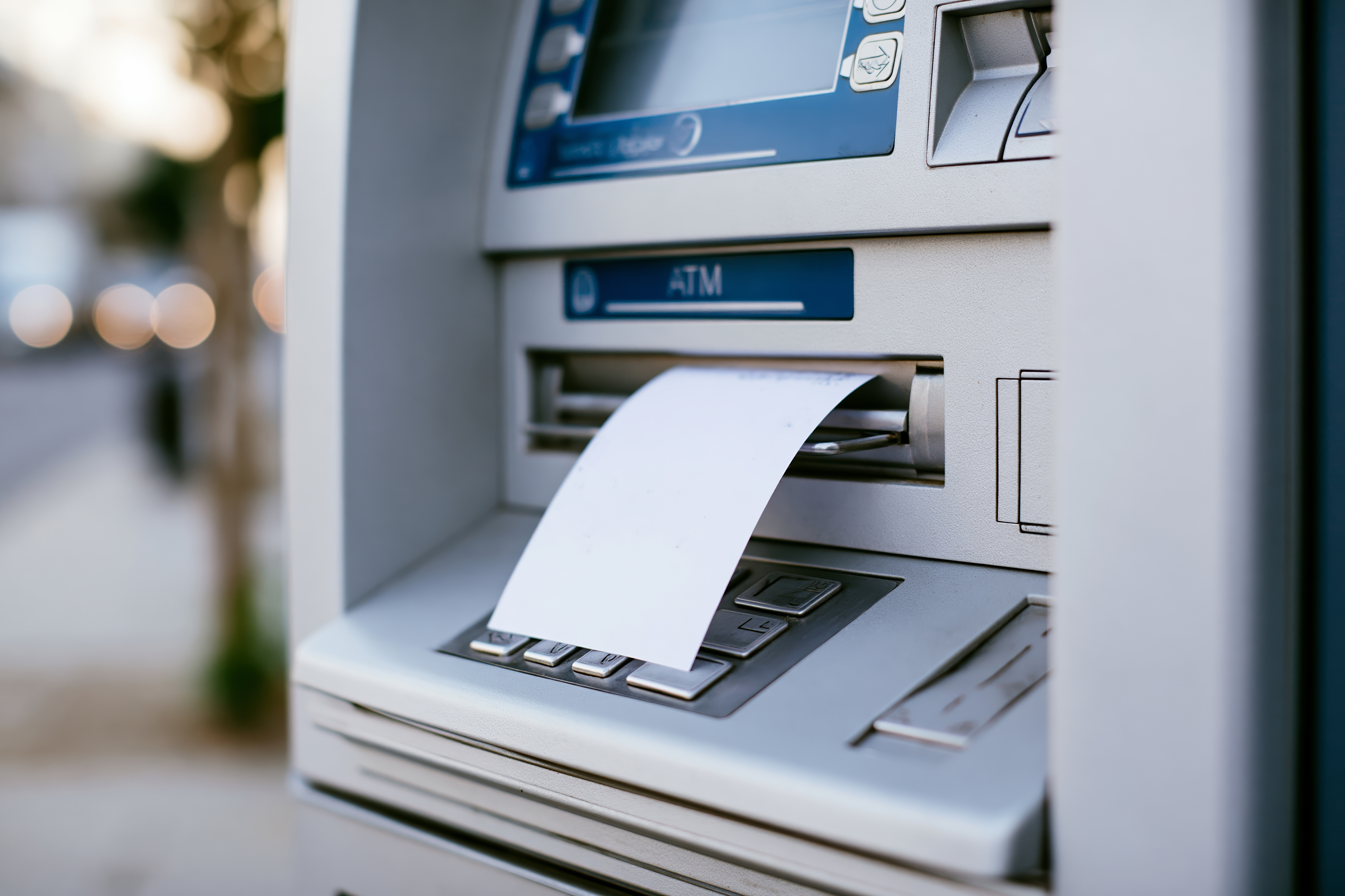 ATM machine dispensing cash with receipt printing out, street view