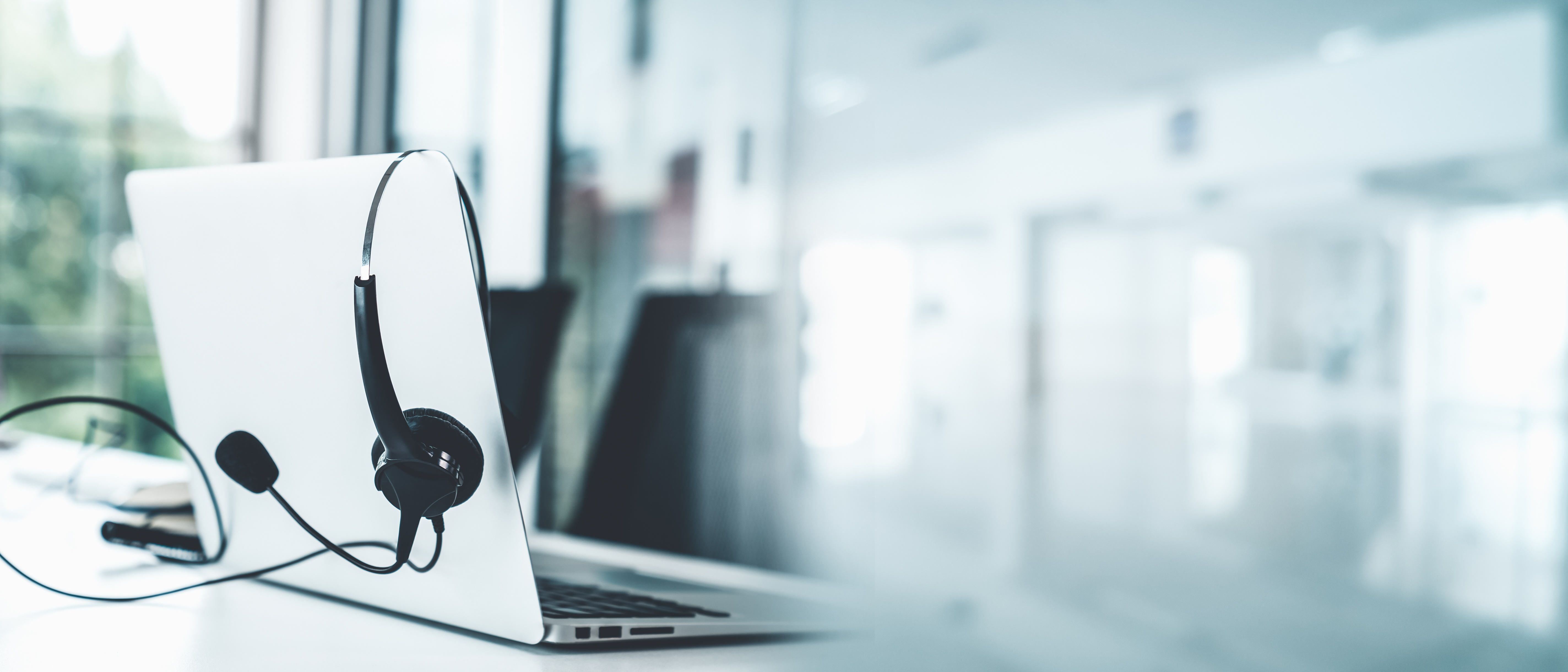 Headset with microphone on laptop at office desk with city skyline view