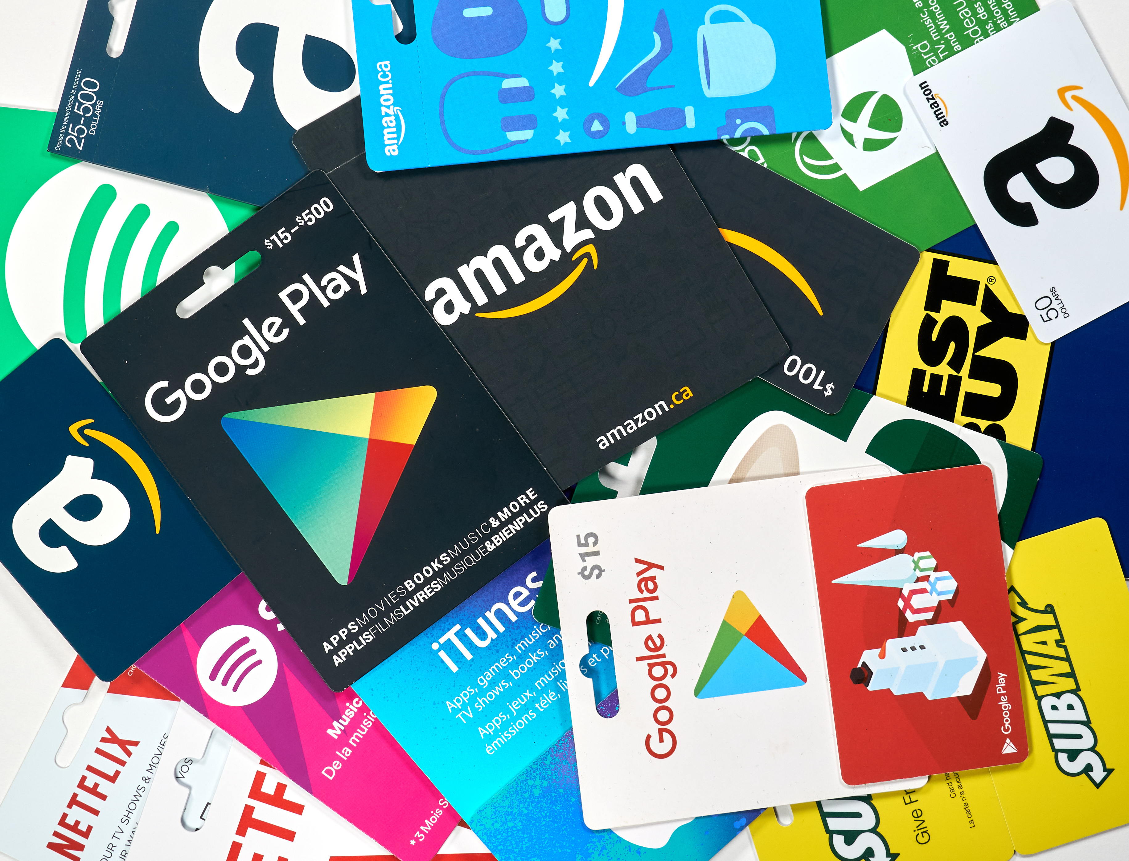 Collection of digital gift cards including Amazon, Google Play, iTunes, and Subway displayed overlapping on white background