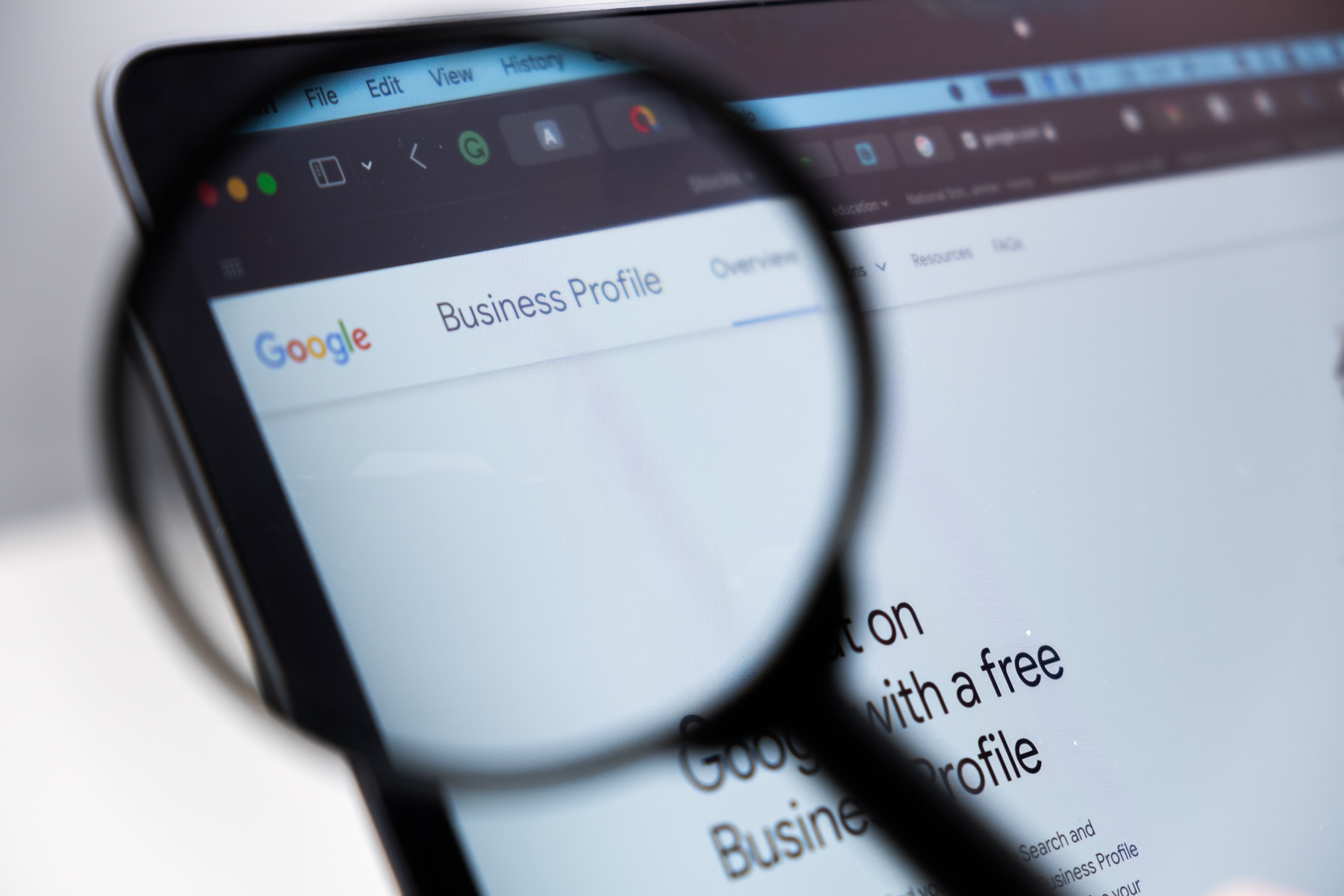 Magnifying glass zooming in on Google Business Profile webpage on computer monitor
