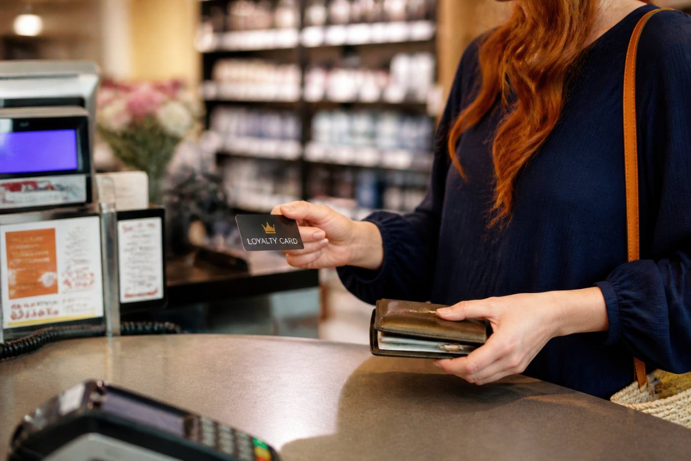 Customer presenting loyalty card at retail checkout counter