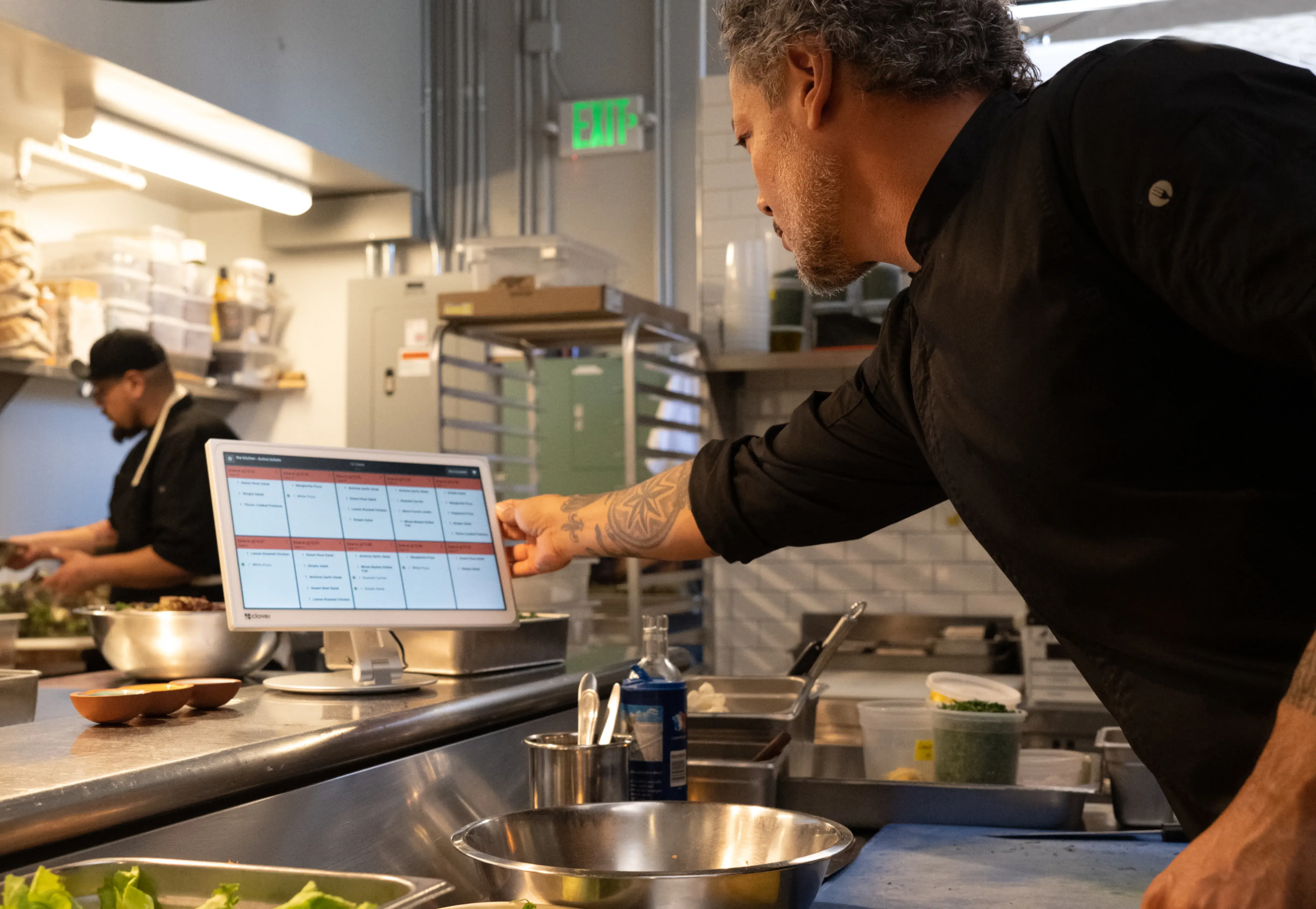 Chef reviews digital schedule on tablet in professional kitchen during service
